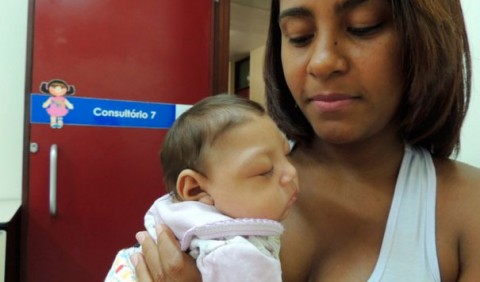 Mãe segurando seu bebê no colo na porta de um consultório médico
