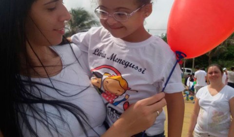 Mulher com garotinha no colo, segurando um balão vermelho