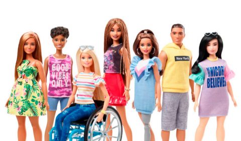 Seis bonecas Barbie dispostas lado a lado e um boneco Ken. Ao centro, uma Barbie em cadeira de rodas e outra com uma perna mecânica.